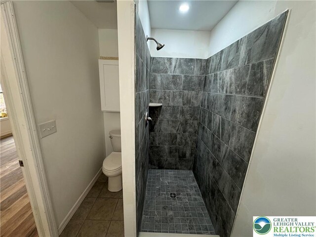 bathroom with tile patterned floors, a stall shower, and toilet