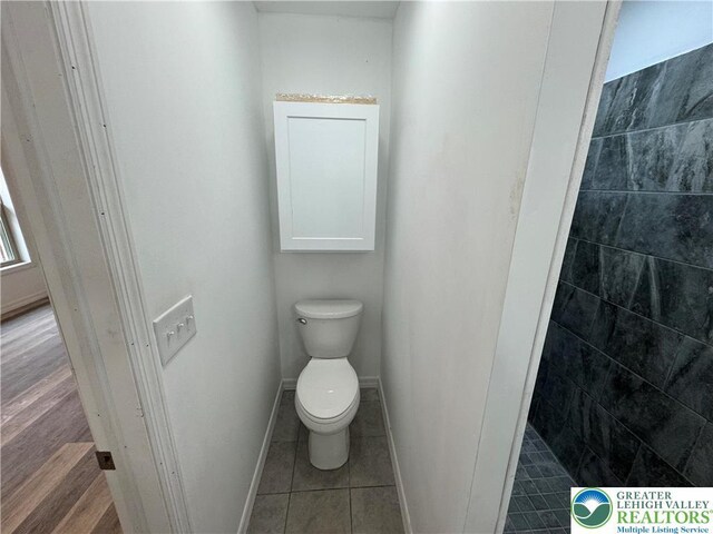 bathroom featuring baseboards, tile patterned floors, and toilet