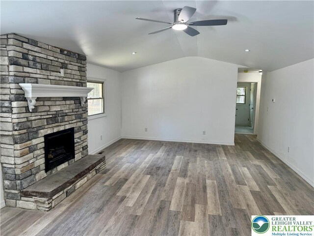 unfurnished living room with a large fireplace, ceiling fan, a wealth of natural light, and lofted ceiling