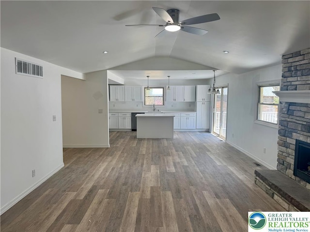 unfurnished living room featuring wood finished floors, a fireplace, visible vents, a ceiling fan, and lofted ceiling