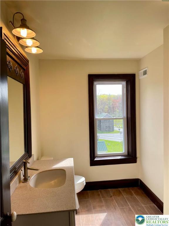 bathroom featuring toilet, visible vents, vanity, and baseboards