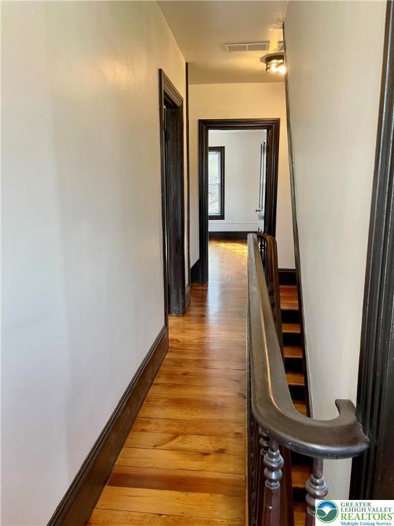 hallway featuring light wood-style floors, visible vents, and baseboards