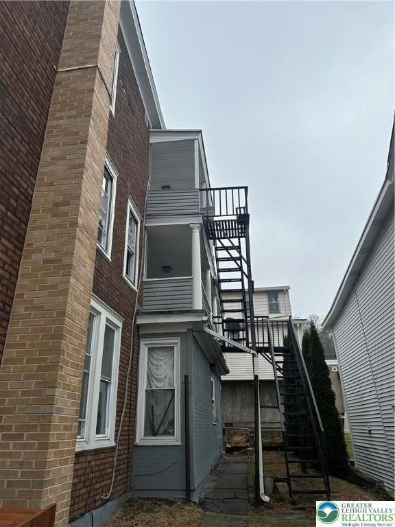 view of side of property with stairway and brick siding