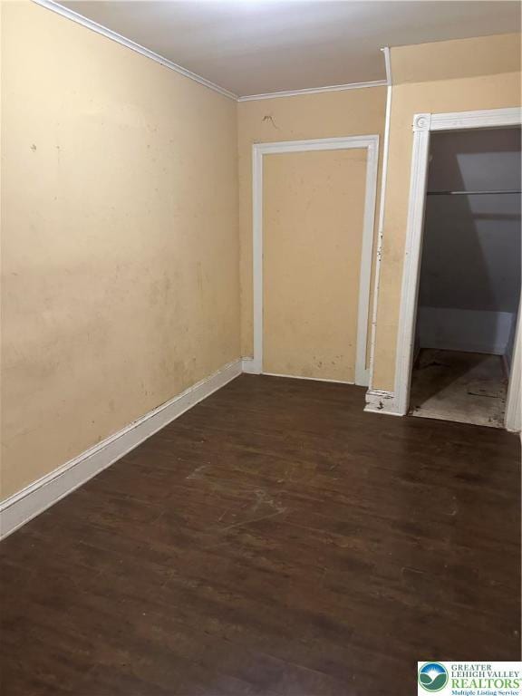 unfurnished bedroom with dark wood-type flooring, baseboards, ornamental molding, and a closet