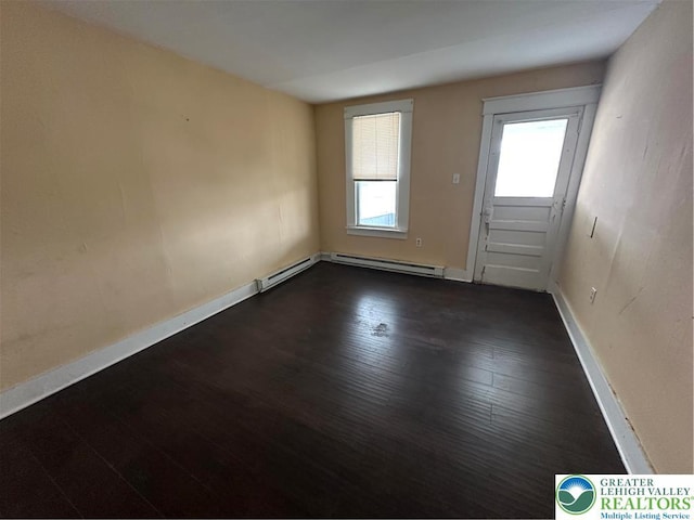 empty room featuring dark wood-style floors, baseboards, and a baseboard radiator