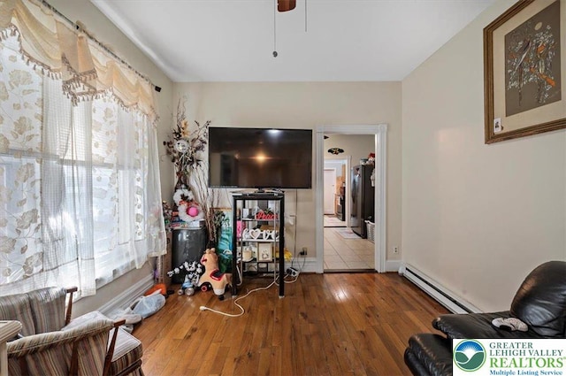 sitting room with ceiling fan, hardwood / wood-style flooring, and a baseboard radiator