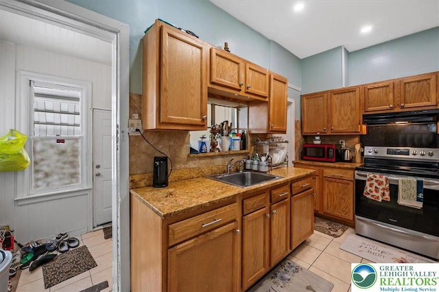 kitchen with electric stove, tasteful backsplash, light tile patterned floors, under cabinet range hood, and a sink