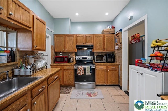 kitchen featuring electric stove, tasteful backsplash, brown cabinetry, and a sink
