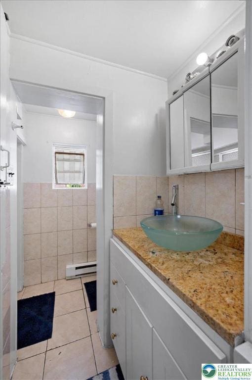 bathroom featuring tile walls, vanity, tile patterned floors, crown molding, and baseboard heating
