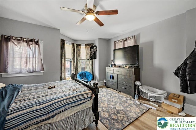bedroom with ceiling fan, wood finished floors, and baseboards