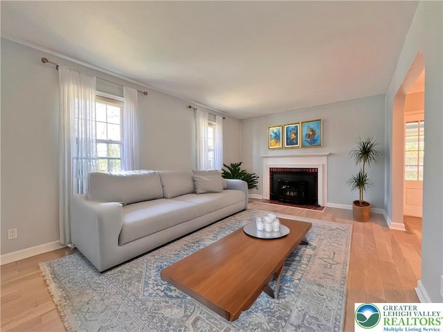 living room featuring a fireplace, light wood-style floors, and baseboards