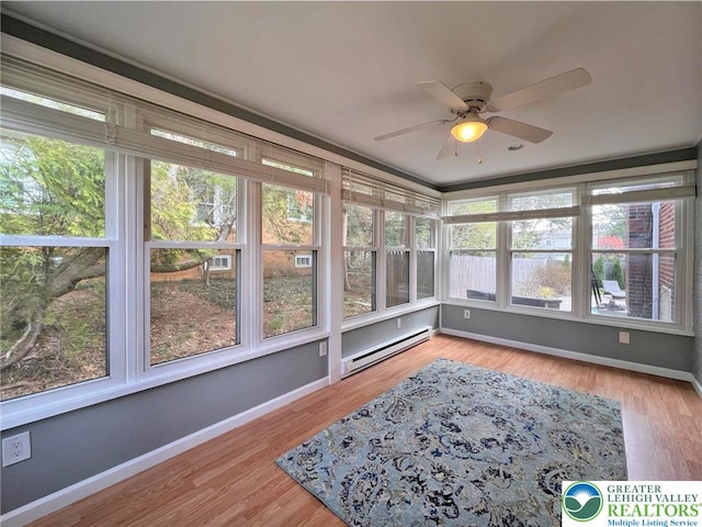 sunroom featuring baseboards, wood finished floors, and a baseboard radiator