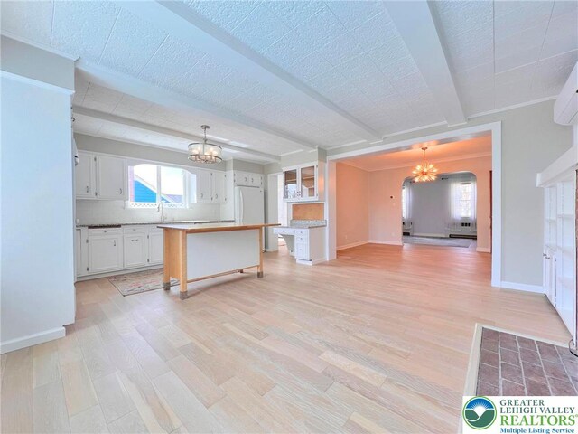 unfurnished living room featuring a chandelier, light wood-type flooring, and baseboards