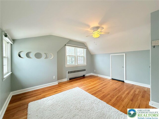 bonus room with baseboards, radiator, ceiling fan, and light wood finished floors