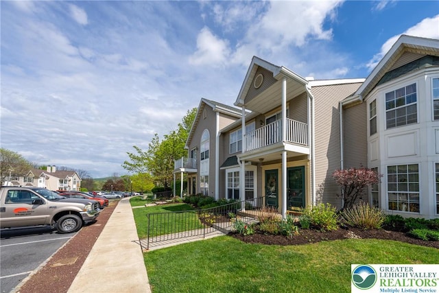 view of side of property with a residential view, uncovered parking, and a lawn