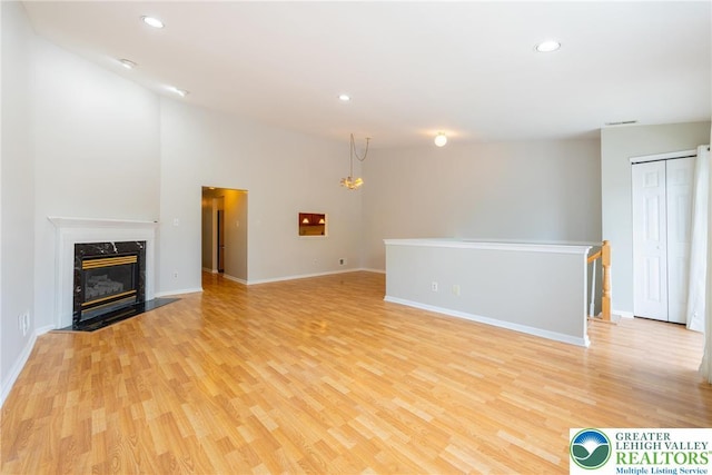 unfurnished living room featuring a premium fireplace, recessed lighting, light wood-style flooring, and baseboards