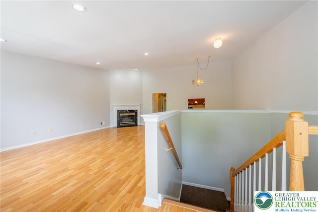 stairs featuring wood finished floors, recessed lighting, a premium fireplace, and baseboards