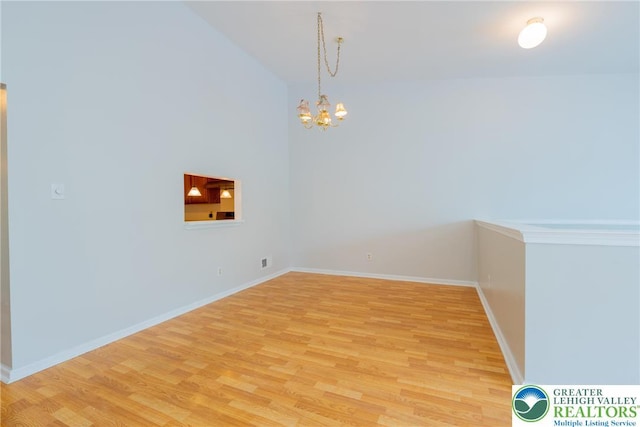 unfurnished dining area featuring lofted ceiling, a chandelier, light wood-type flooring, and baseboards