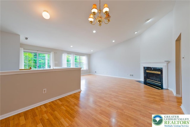 unfurnished living room featuring vaulted ceiling, visible vents, light wood-style flooring, and a high end fireplace