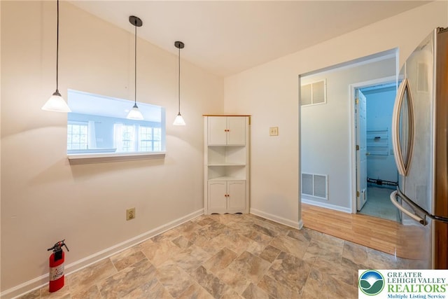 empty room with baseboards, visible vents, and stone finish floor