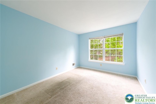 carpeted spare room featuring baseboards and visible vents