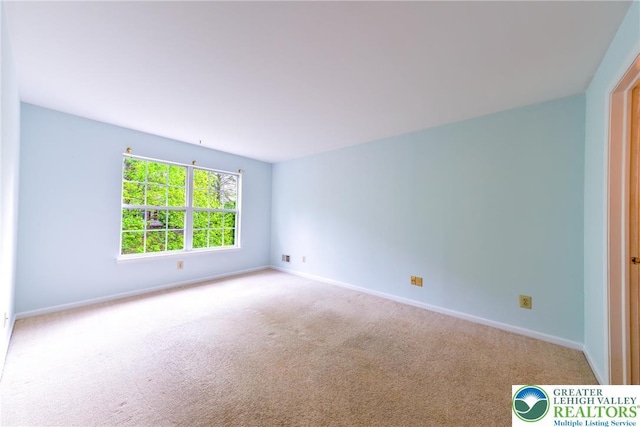 carpeted spare room featuring baseboards