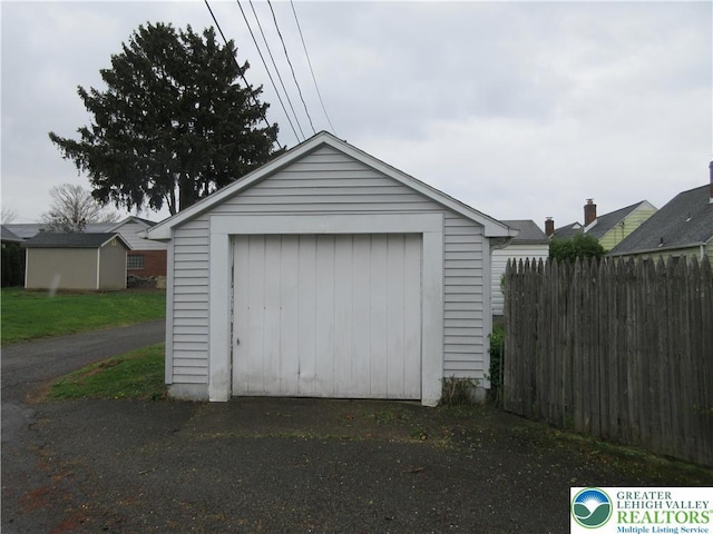 detached garage featuring fence and aphalt driveway