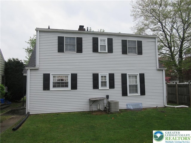 back of property with fence, a chimney, a yard, and central AC unit