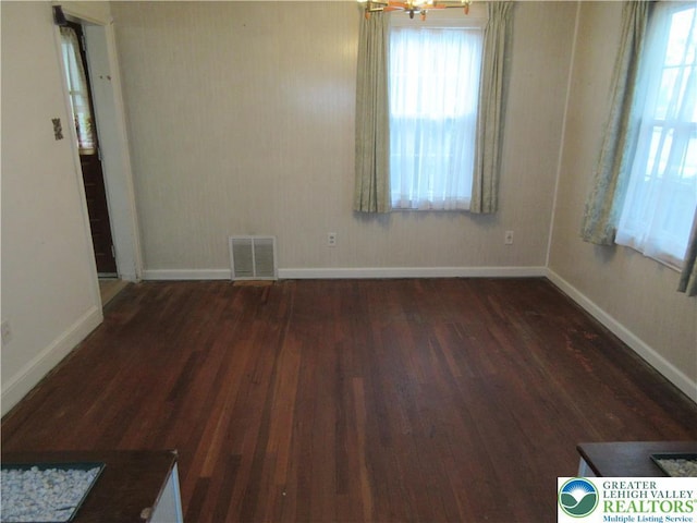 spare room with visible vents, baseboards, wood finished floors, and plenty of natural light