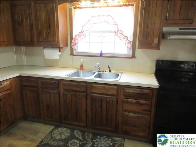 kitchen featuring a sink, black range with electric stovetop, under cabinet range hood, and light countertops