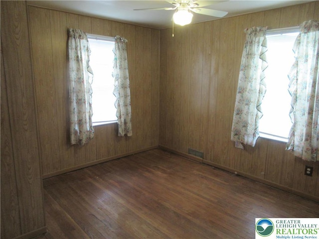 unfurnished room with wood finished floors, a ceiling fan, and visible vents