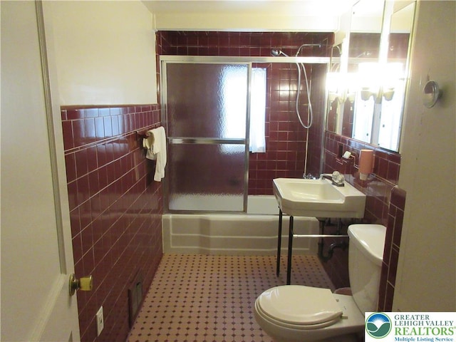 full bathroom featuring tile walls, a healthy amount of sunlight, enclosed tub / shower combo, and a sink