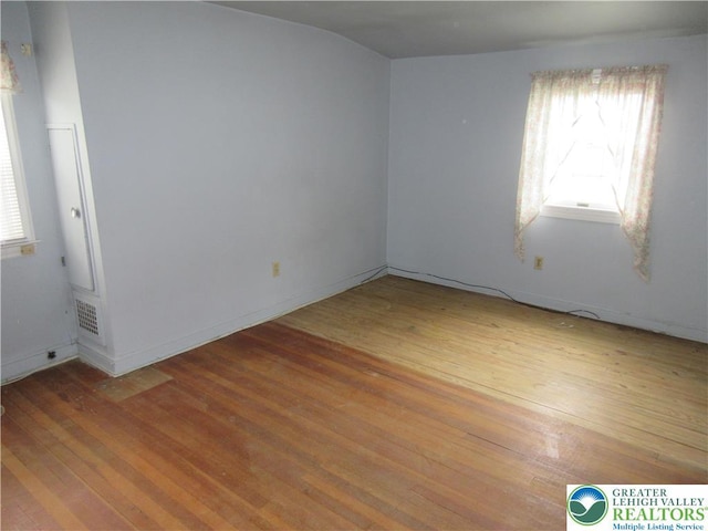unfurnished room with hardwood / wood-style floors, visible vents, and a healthy amount of sunlight