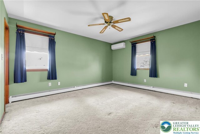 carpeted empty room featuring a ceiling fan, a wall mounted AC, and baseboards