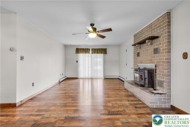 unfurnished living room with a baseboard heating unit, a wood stove, a ceiling fan, baseboards, and wood finished floors
