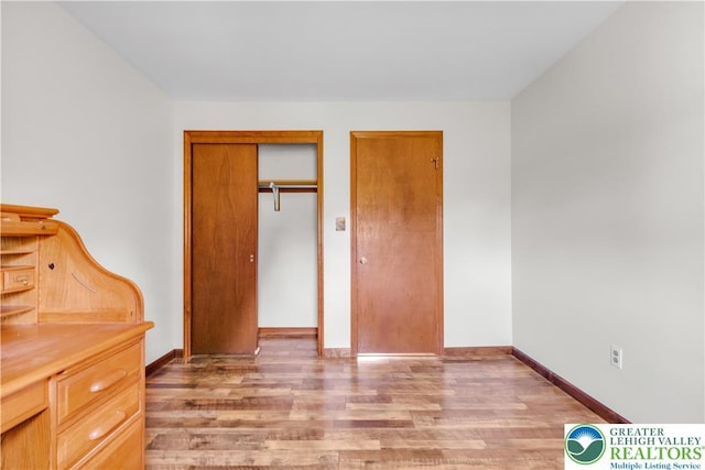 unfurnished bedroom featuring a closet, baseboards, and light wood-type flooring