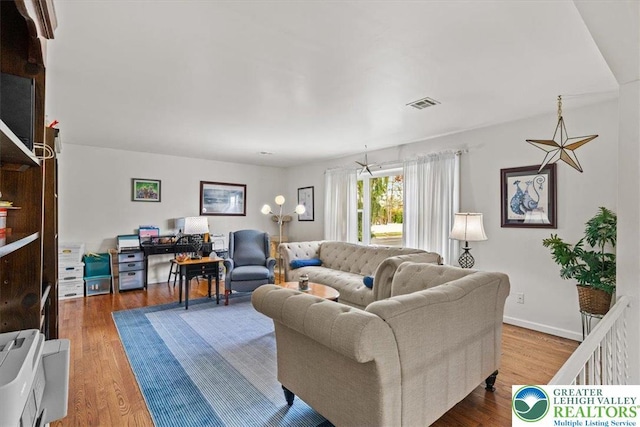 living room with visible vents, wood finished floors, and baseboards