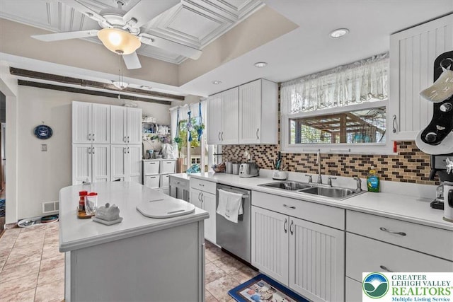 kitchen featuring a sink, ceiling fan, a center island, light countertops, and stainless steel dishwasher