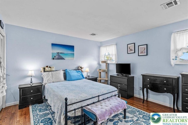 bedroom featuring baseboards, visible vents, and wood finished floors