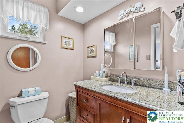 bathroom with toilet, vanity, and baseboards