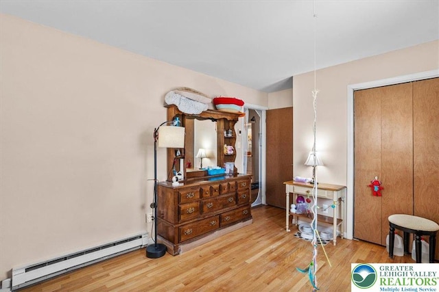bedroom with a baseboard radiator and wood finished floors