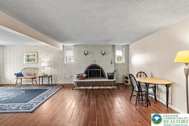 living room featuring a textured ceiling, wood finished floors, and brick wall