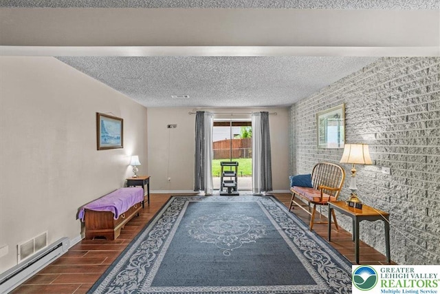 sitting room with brick wall, baseboards, a textured ceiling, wood finished floors, and a baseboard radiator