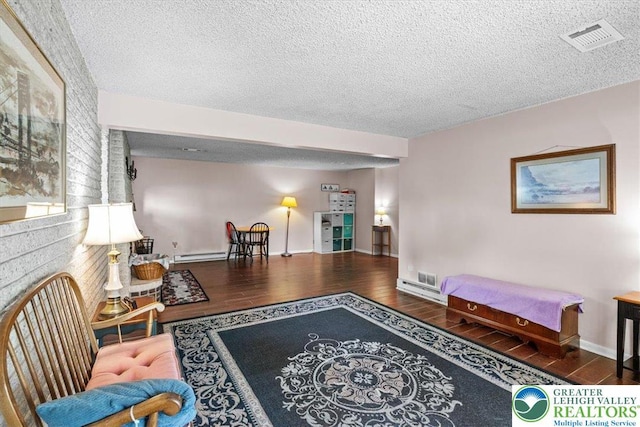 interior space with visible vents, baseboards, a textured ceiling, baseboard heating, and wood finished floors
