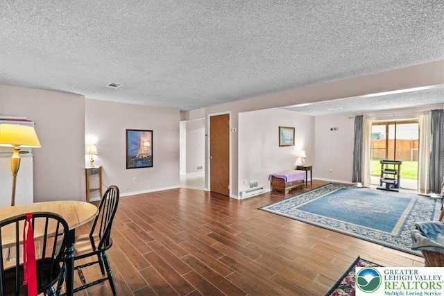 living room featuring a textured ceiling, wood finished floors, visible vents, and baseboards