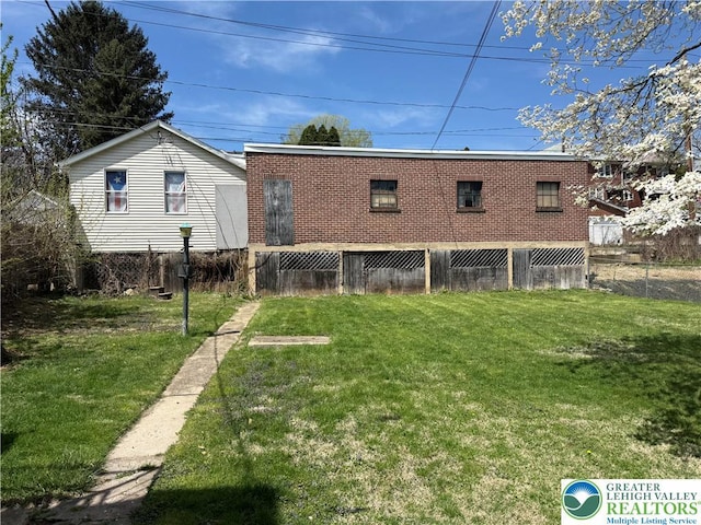 rear view of property featuring a yard and fence