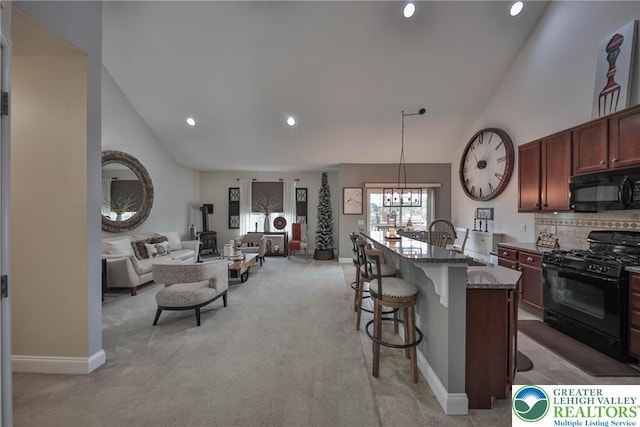 kitchen featuring light colored carpet, black appliances, stone counters, a kitchen bar, and open floor plan