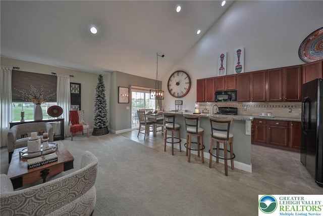 kitchen featuring decorative backsplash, a breakfast bar, black appliances, recessed lighting, and high vaulted ceiling