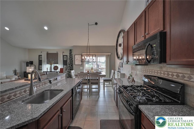 kitchen featuring dark stone counters, an inviting chandelier, a sink, tasteful backsplash, and black appliances