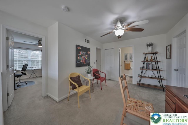 interior space featuring baseboards, visible vents, a ceiling fan, and light colored carpet